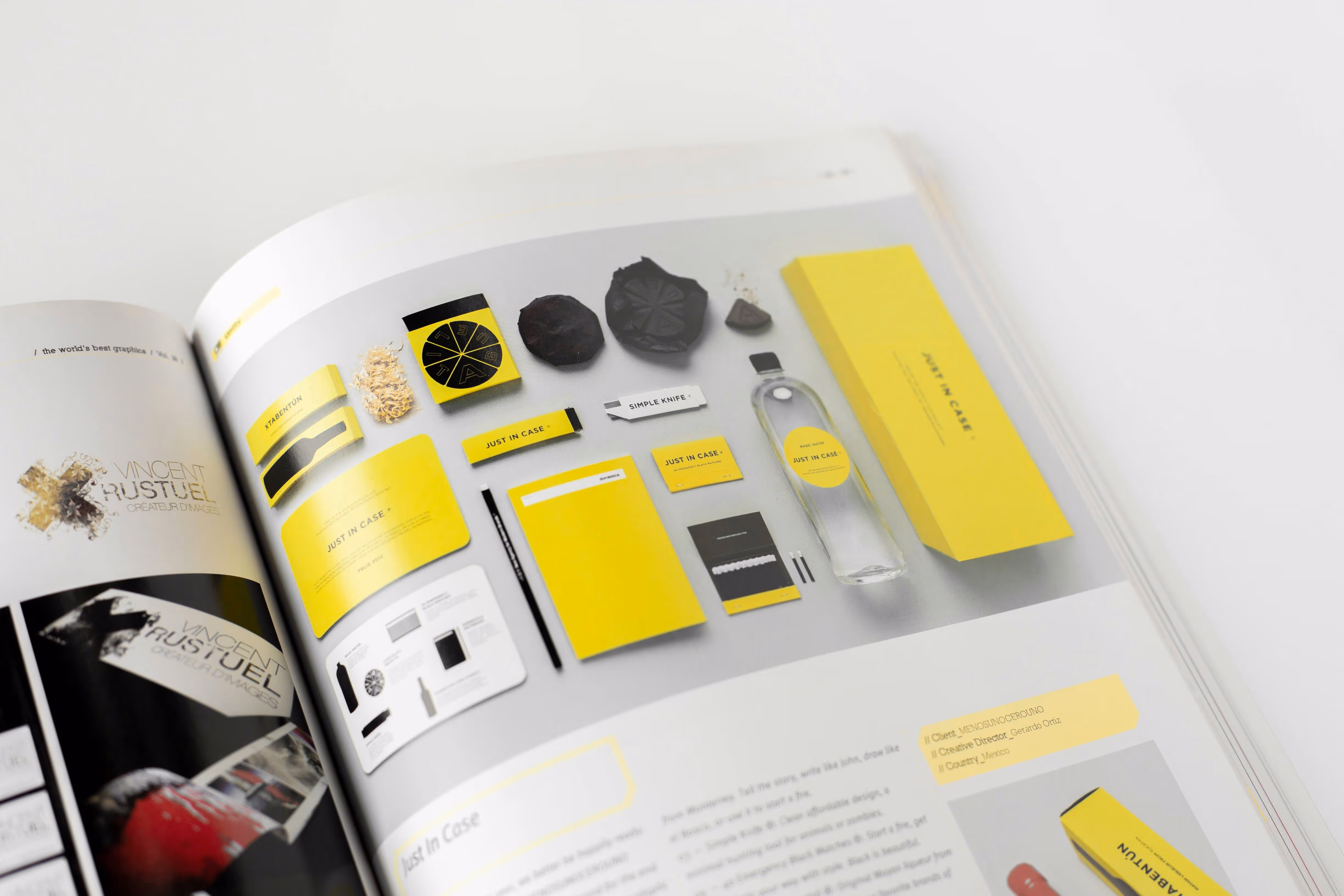Open magazine showing a page with a flat lay of yellow and black branded items including packaging, stationery, a water bottle, and a knife.